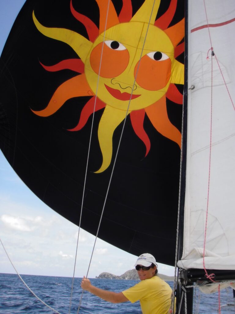 Yellow, red and orange smiling sun spinnaker flying on the sailboat O'dege